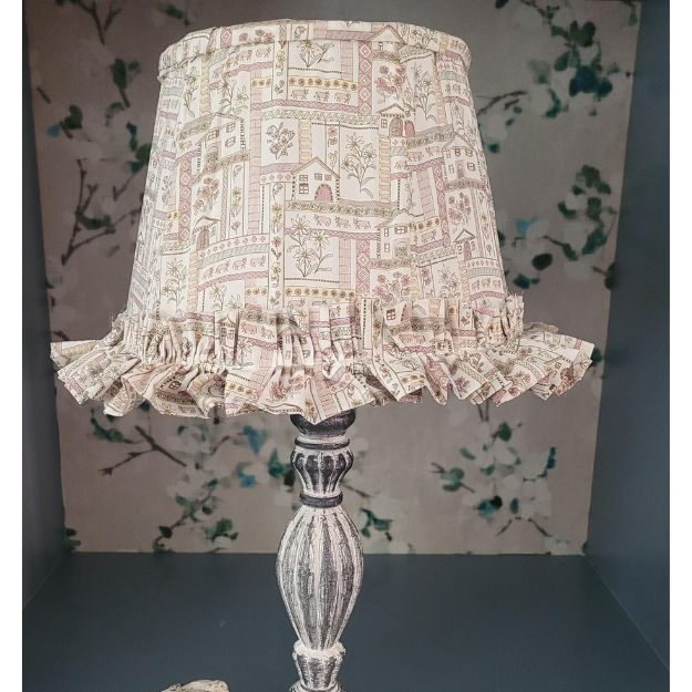 Tapered hand-sewn fabric French drum lampshade featuring alpine flowers and animals in a whimsical design. Finished with ruffle trim for a charming touch, adding a unique and cosy element to any table lamp. Crafted with Liberty London fabric.