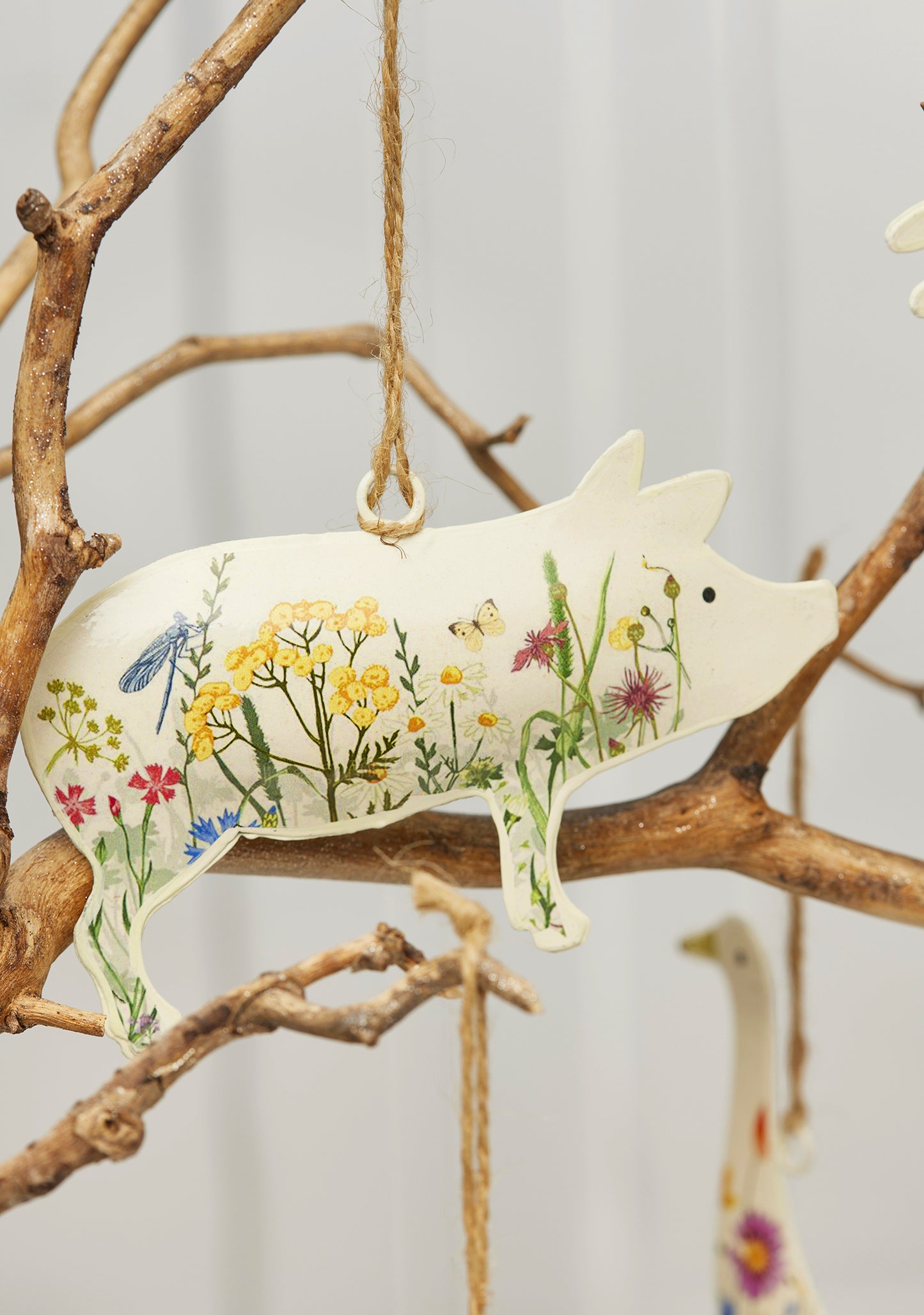 Cream hand-painted metal farm animal decorations — cow, pig, goose, hare and sheep — with floral meadow design and jute hanging string, grouped for display.