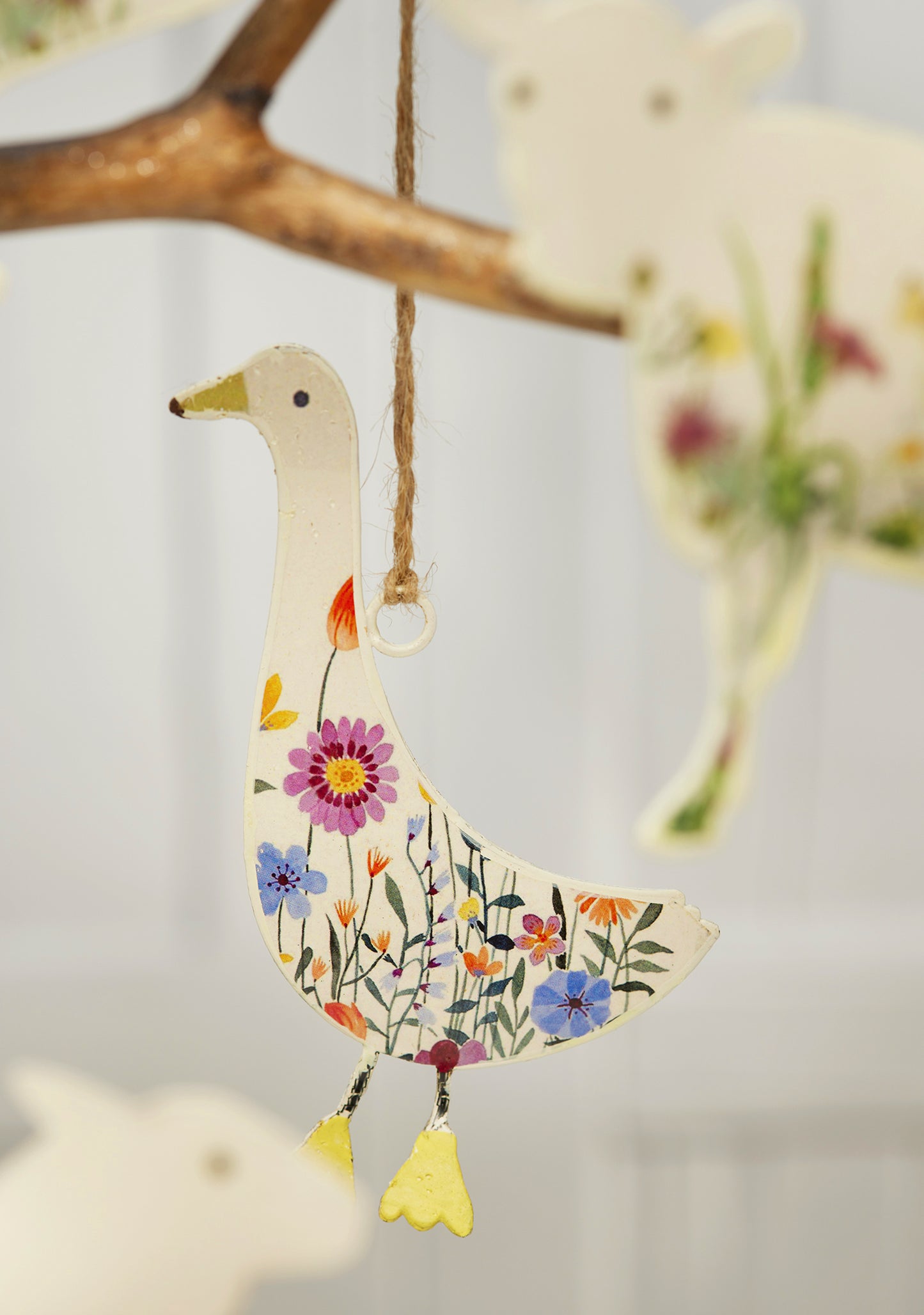 Cream hand-painted metal farm animal decorations — cow, pig, goose, hare and sheep — with floral meadow design and jute hanging string, grouped for display.