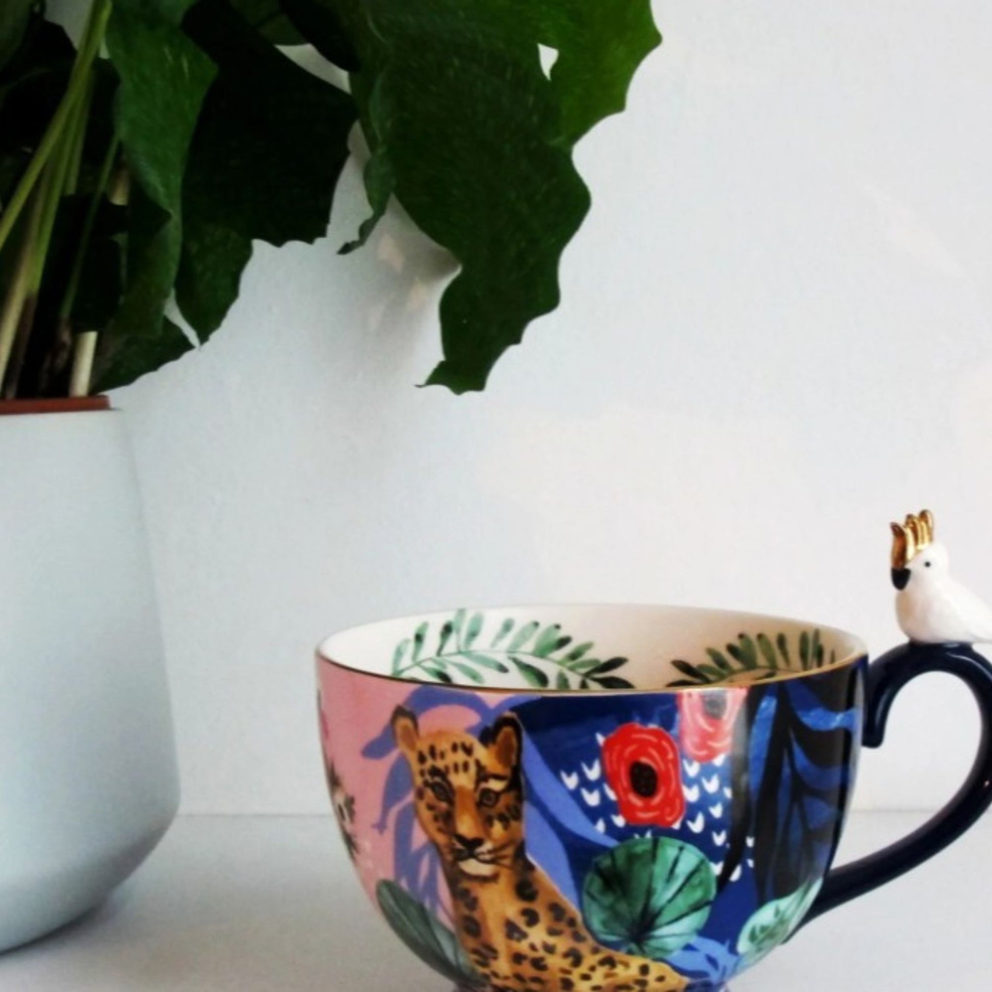 Frida Kahlo tropical porcelain mug with gold parakeet handle, gold signature and leaf print inside.