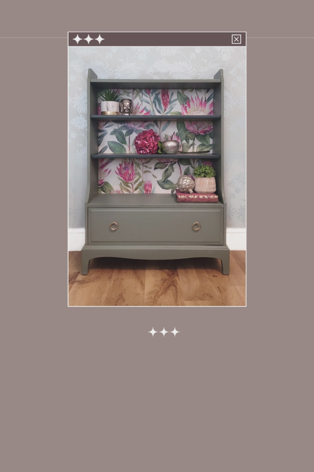 Beautifully upcycled green bookshelf with floral wallpaper backing. The shelves display decorative items and the bottom drawer features elegant gold ring pulls. Perfect for adding a touch of nature-inspired charm to any living room, bedroom, or hallway.