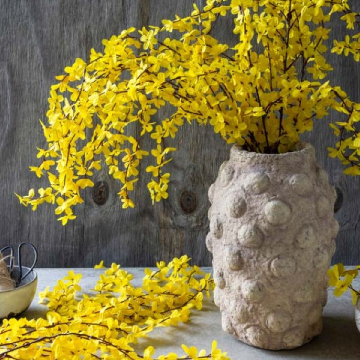 Abigail Ahern Stone Cement Bobble Vase with yellow trailing flowers and branches