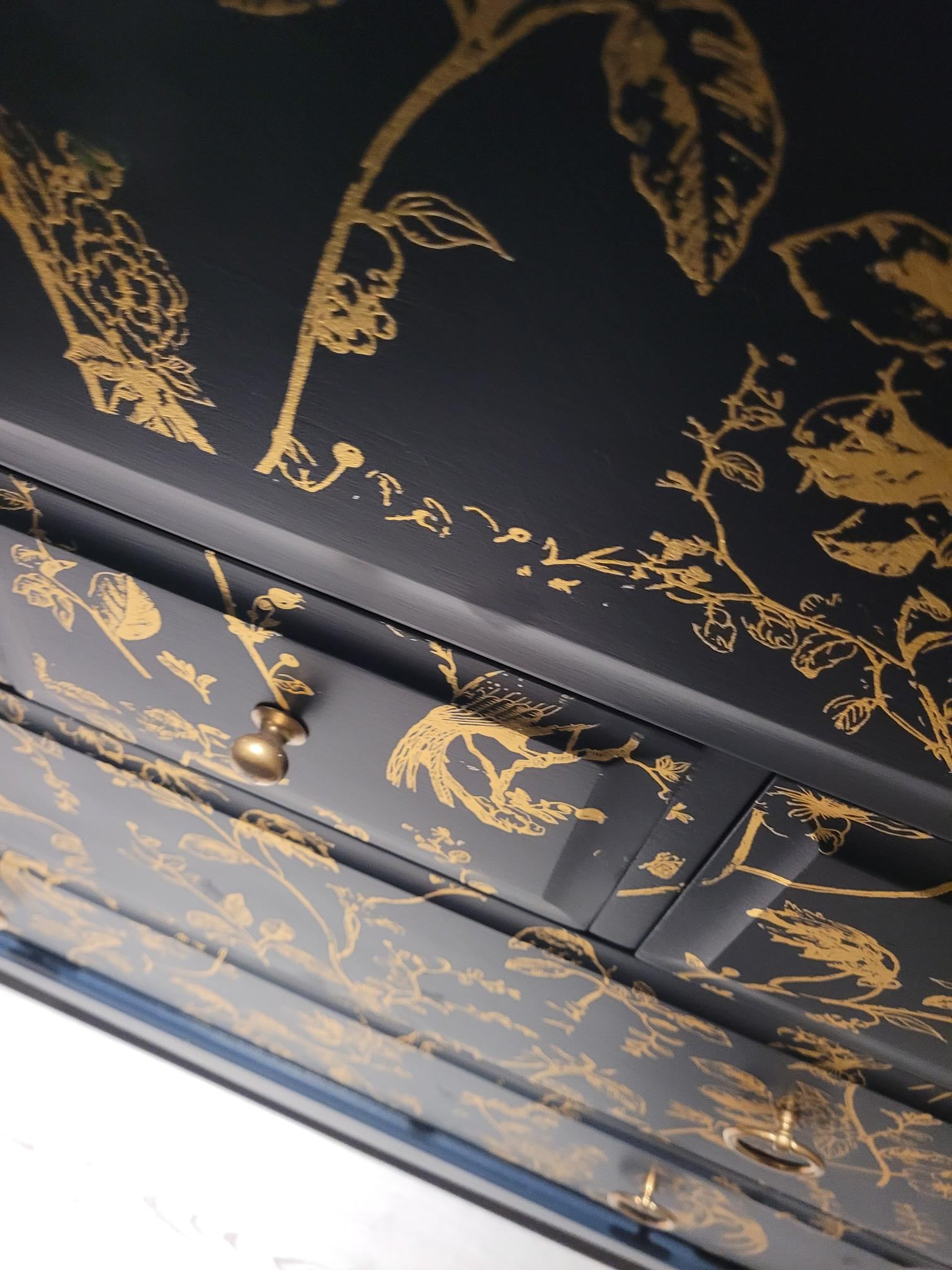 Elegant upcycled navy blue chest of drawers featuring a delicate, hand-painted gold floral design. The drawers are accented with intricate gold knobs, making this piece a sophisticated addition to any living room, bedroom, or hallway.