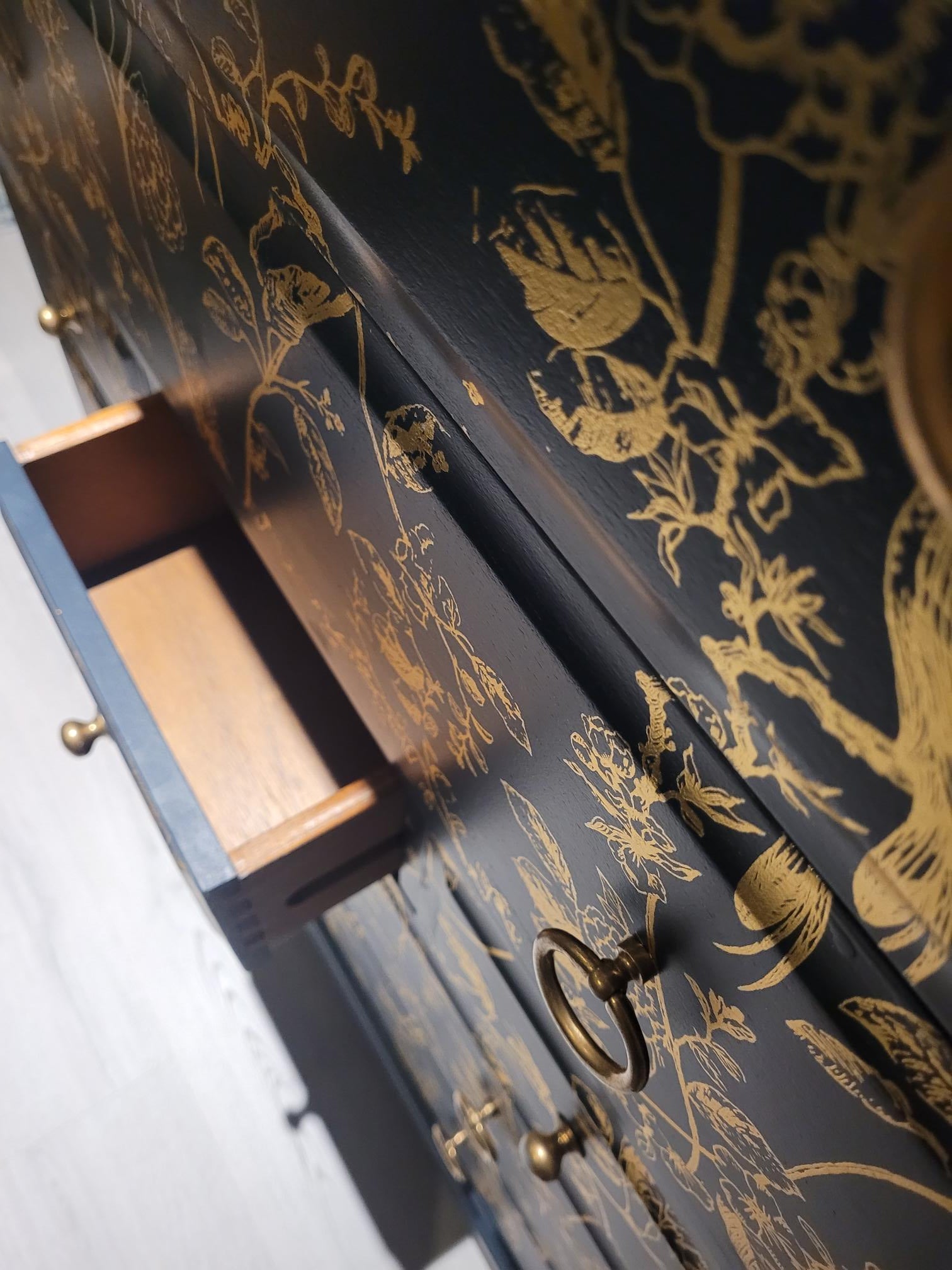 Elegant upcycled navy blue chest of drawers featuring a delicate, hand-painted gold floral design. The drawers are accented with intricate gold knobs, making this piece a sophisticated addition to any living room, bedroom, or hallway.