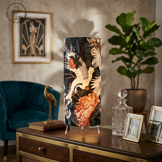 An art deco table lamp in black and organge with elegant swan detail in an oppulent living room on a sideboard with an art deco scallop chair in the background.