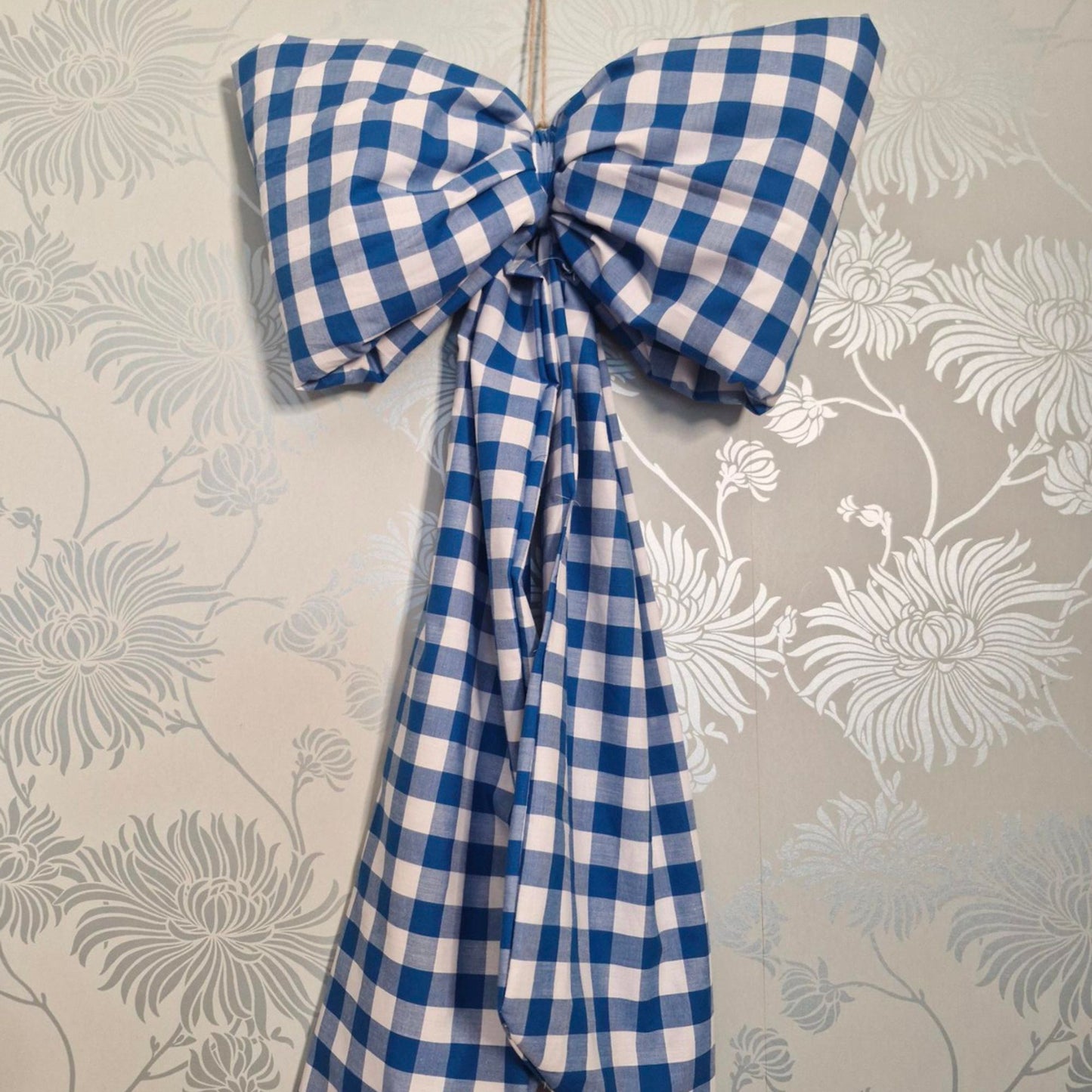 Blue and white checkered bow on a floral wallpaper background