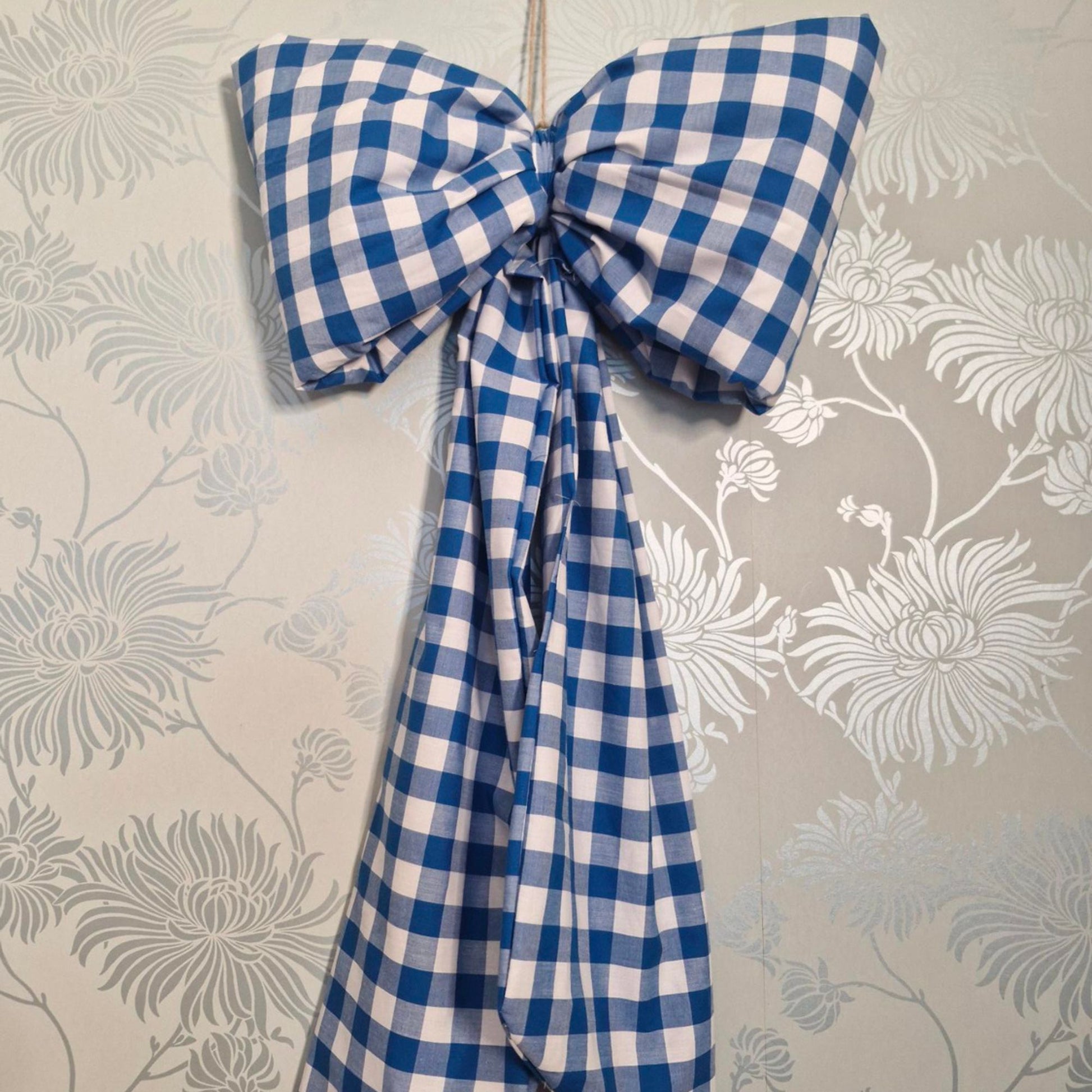 Blue and white checkered bow on a floral wallpaper background