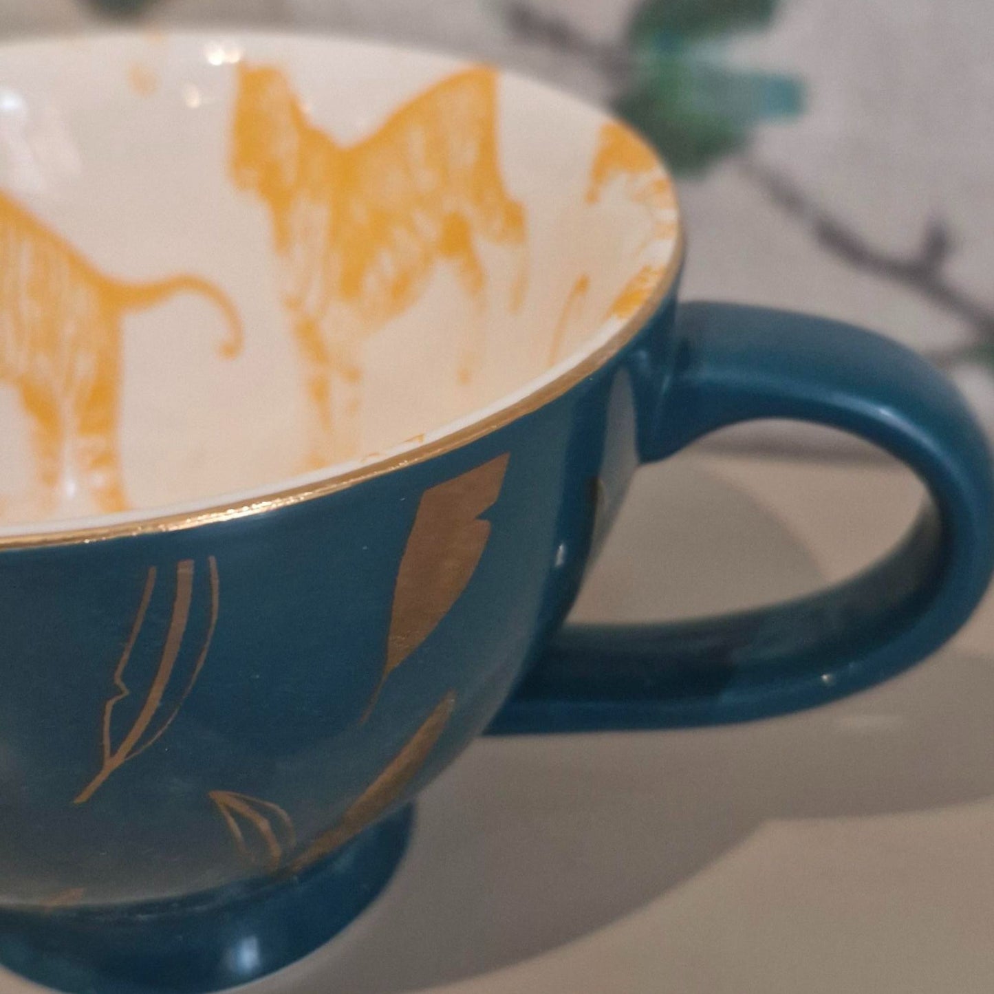 Green / Blue cup with orange tiger illustrations on a white surface