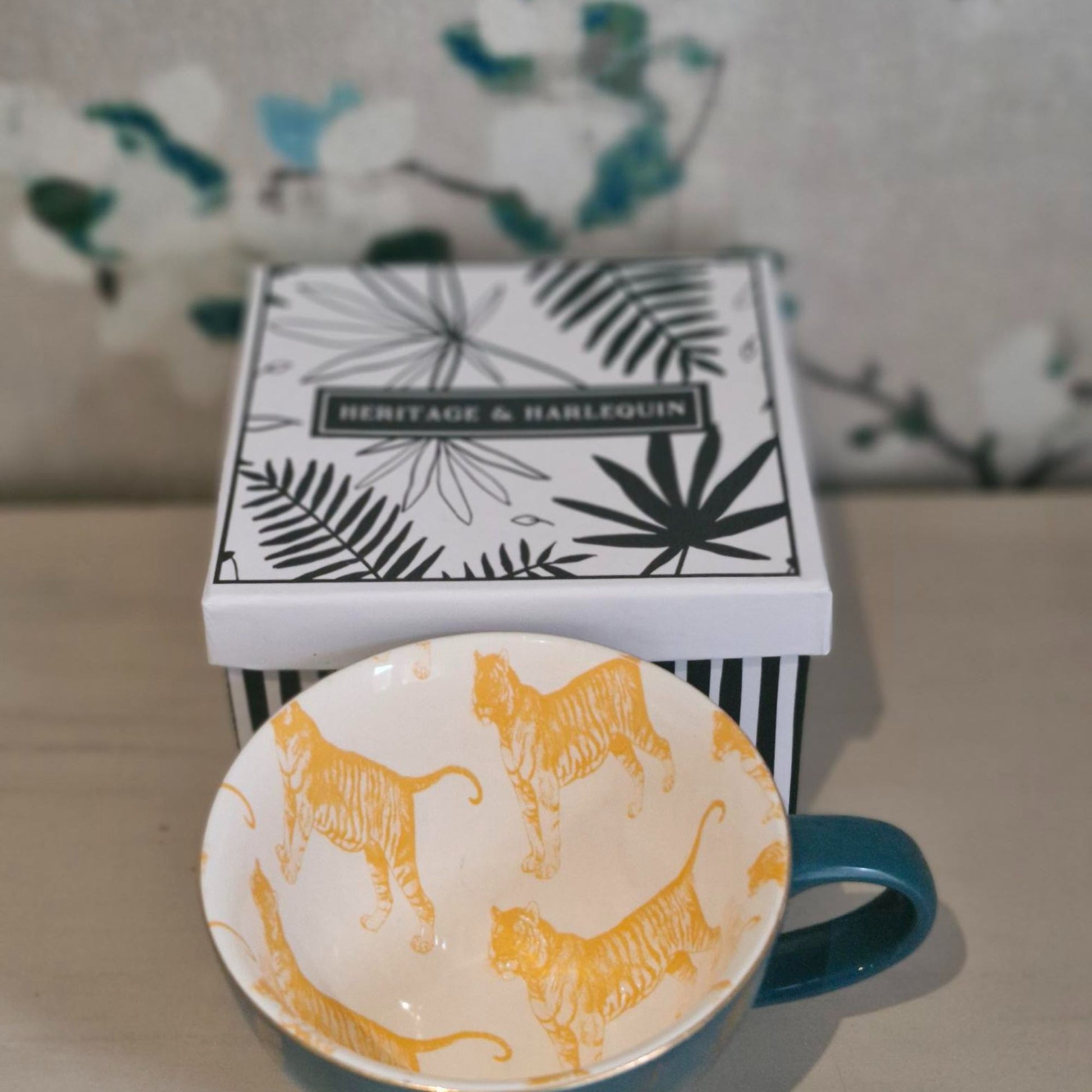 Ceramic cup with tiger design and matching saucer, both featuring 'Heritage & Harlequin' branding.