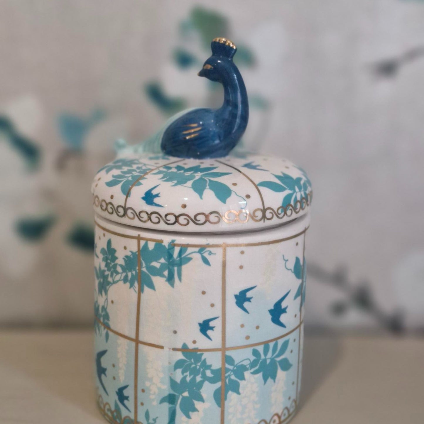 Decorative ceramic jar with peacock design on a blurred background