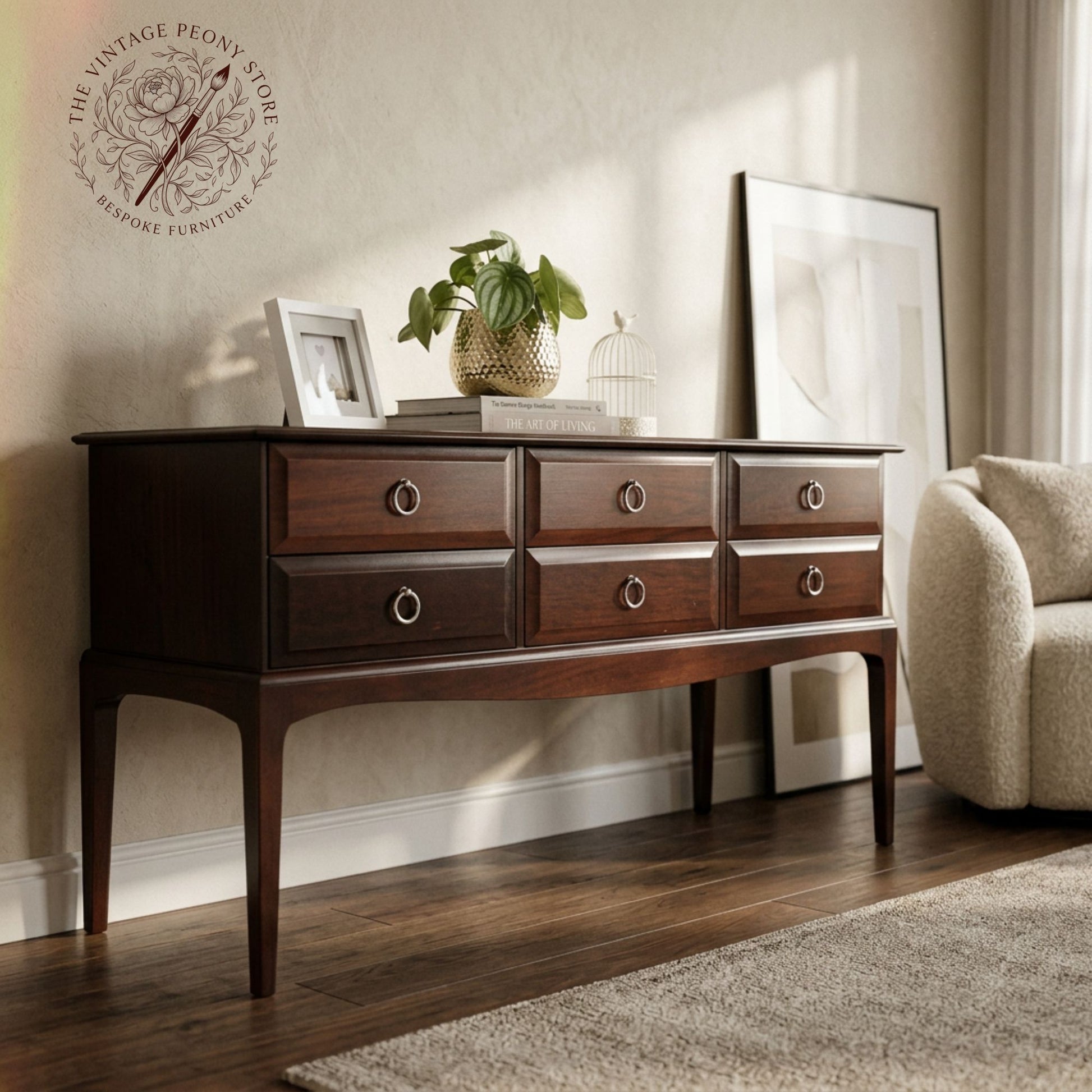 A dark brown Stag  Minstrel wooden console table with six drawers and round metal pulls, styled in a warm, modern living room setting next to a beige armchair.