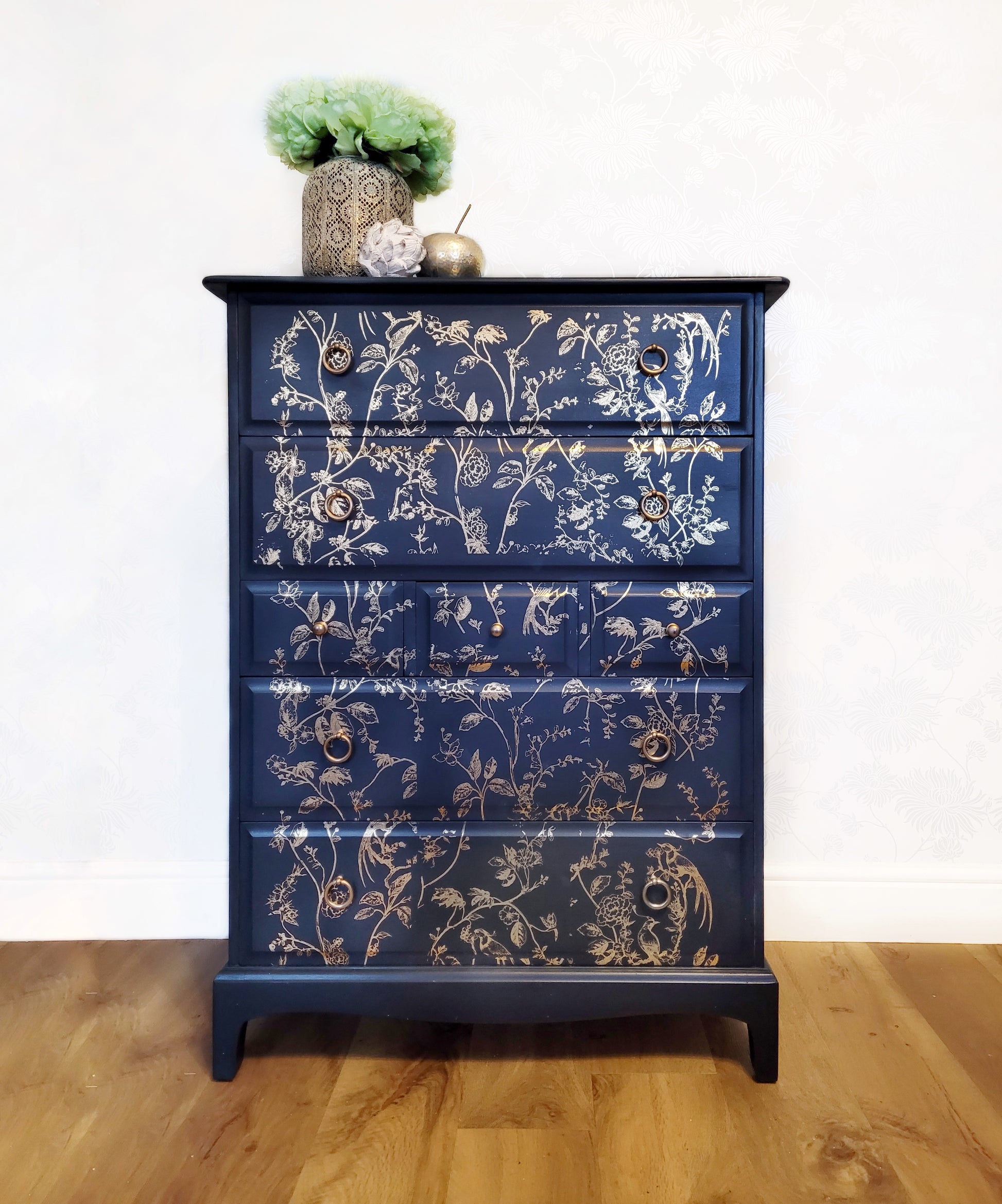 Elegant upcycled navy blue chest of drawers featuring a delicate, hand-painted gold floral design. The drawers are accented with intricate gold knobs, making this piece a sophisticated addition to any living room, bedroom, or hallway.