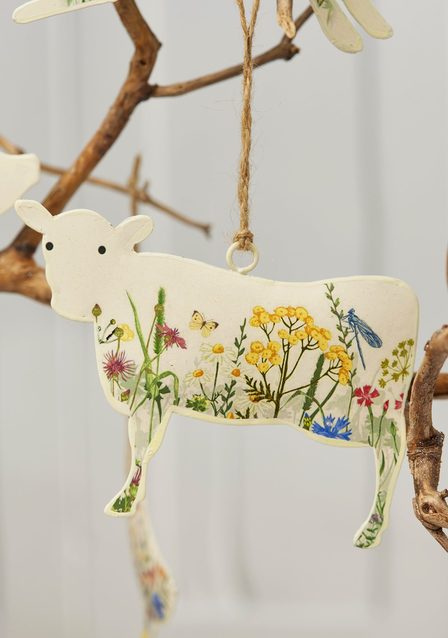 Cream hand-painted metal farm animal decorations — cow, pig, goose, hare and sheep — with floral meadow design and jute hanging string, grouped for display.