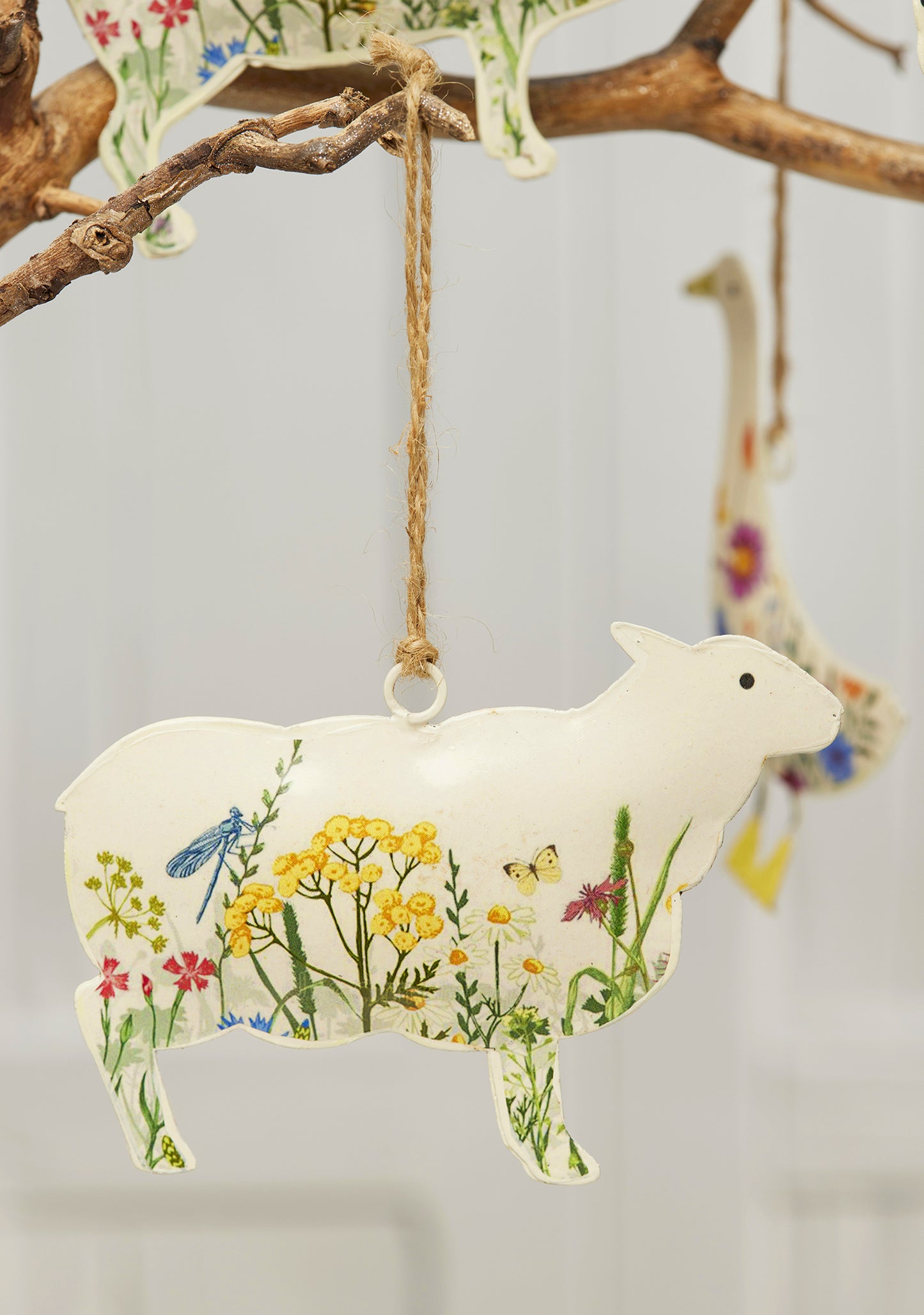 Cream hand-painted metal farm animal decorations — cow, pig, goose, hare and sheep — with floral meadow design and jute hanging string, grouped for display.