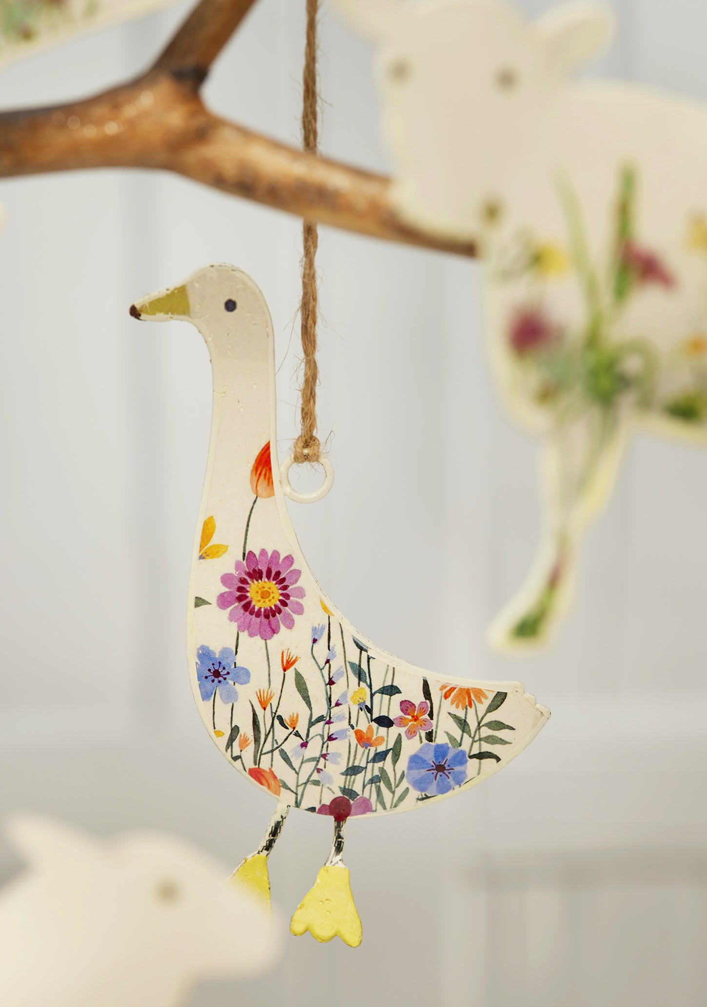 Cream hand-painted metal farm animal decorations — cow, pig, goose, hare and sheep — with floral meadow design and jute hanging string, grouped for display.