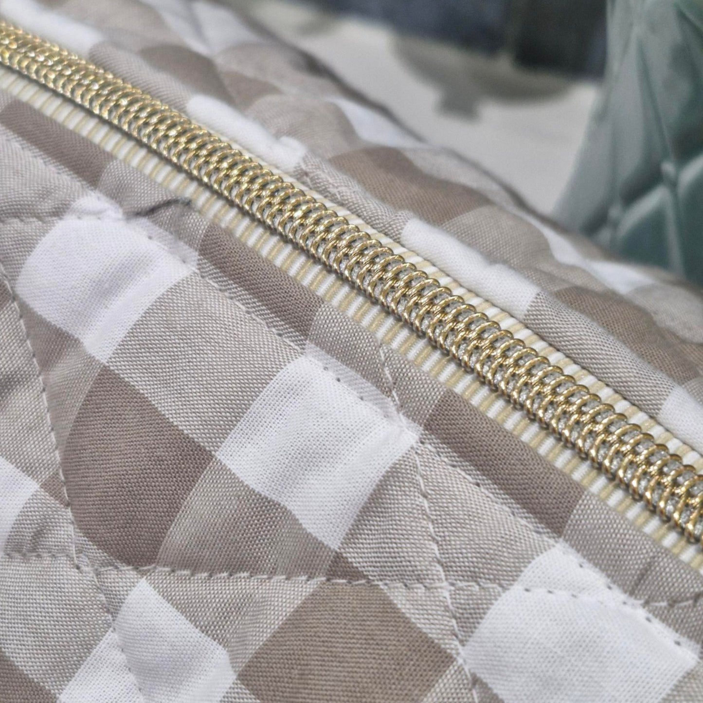Close-up of a gingham quilted bag with a gold zipper