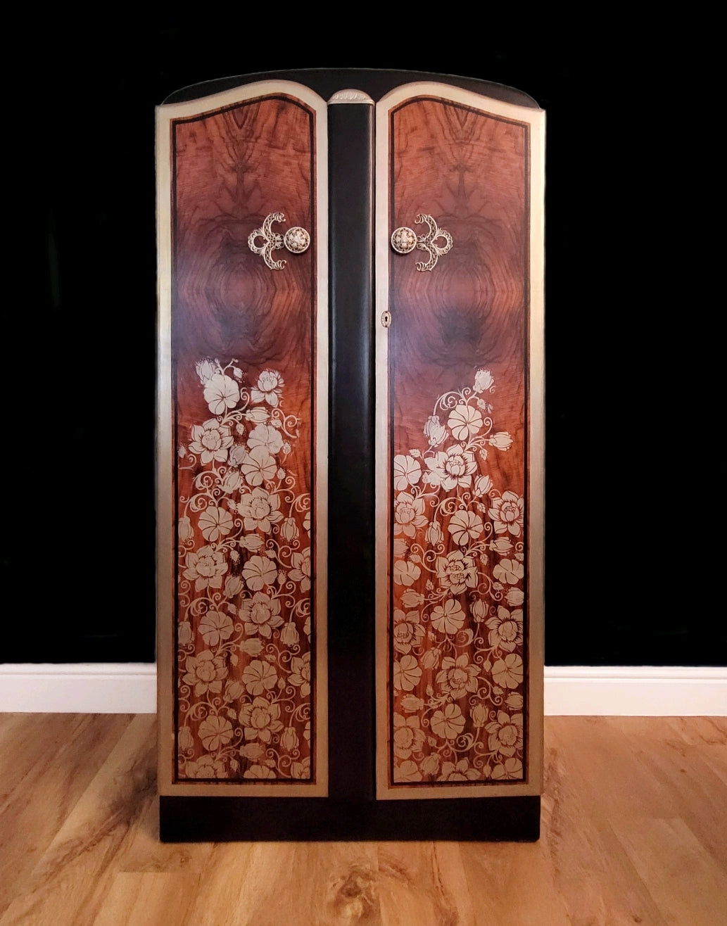 Upcycled Art Deco wardrobe with walnut veneer, black and gold accents, and floral stenciling.