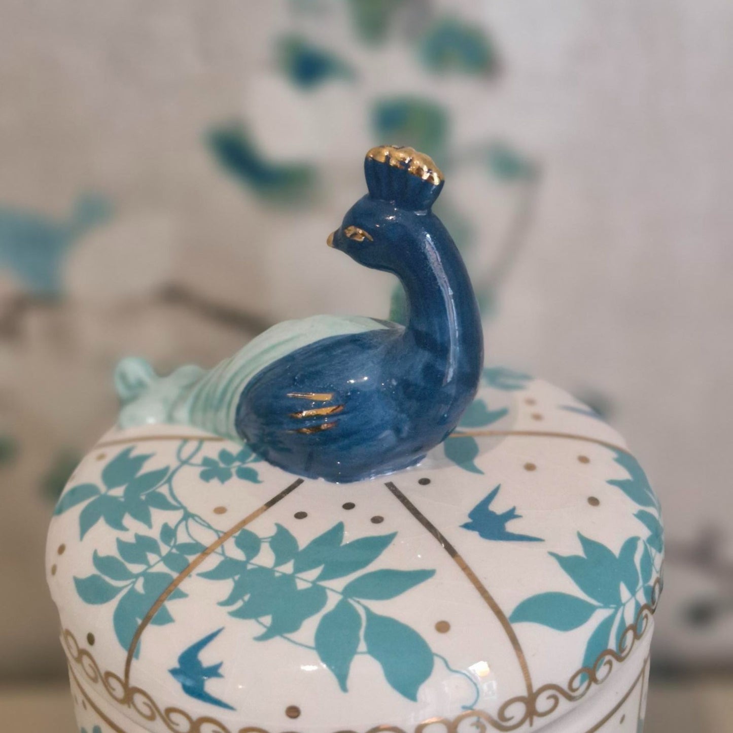 Decorative ceramic jar with peacock design on a blurred background
