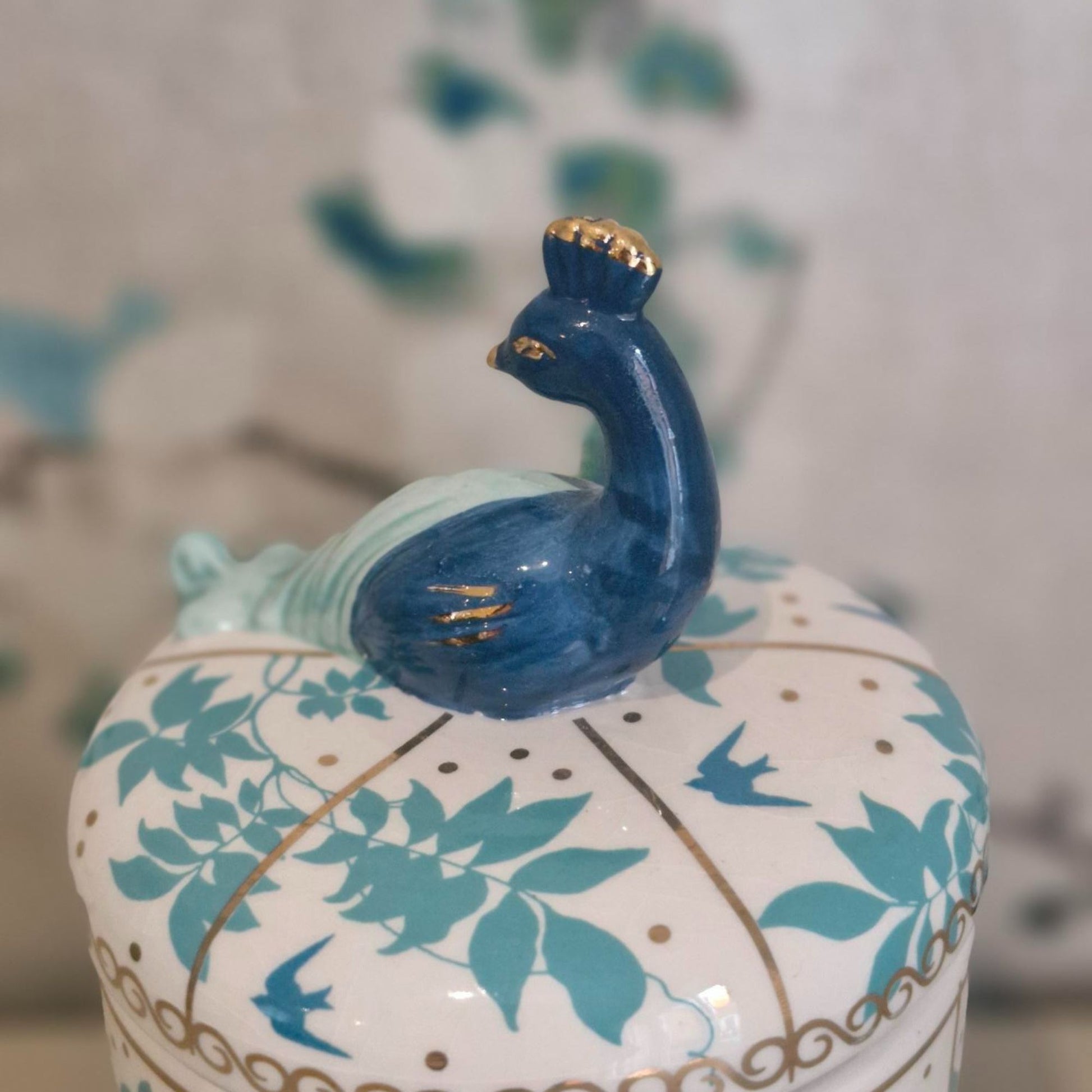 Decorative ceramic jar with peacock design on a blurred background