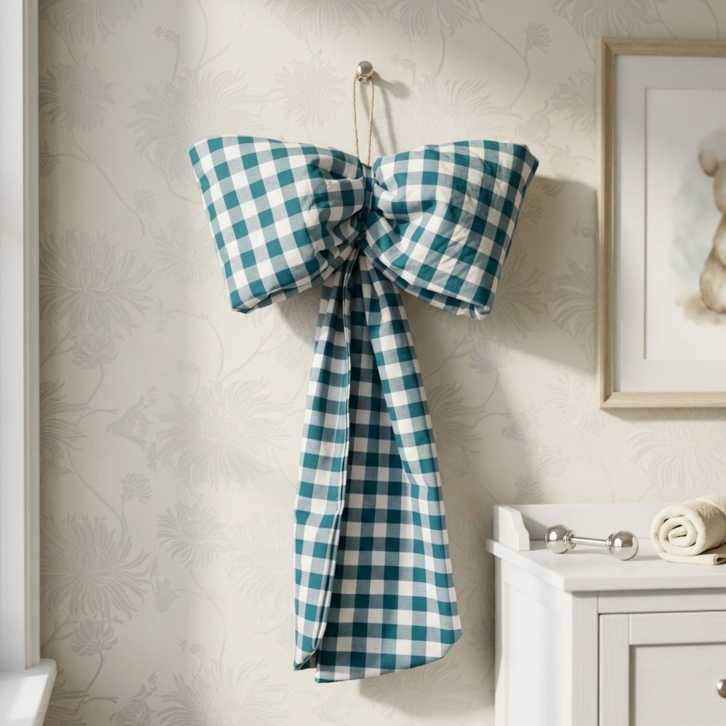 Teal decorative hanging bow located on the wall of a childrens bedroom next to a picture of a teddy bear