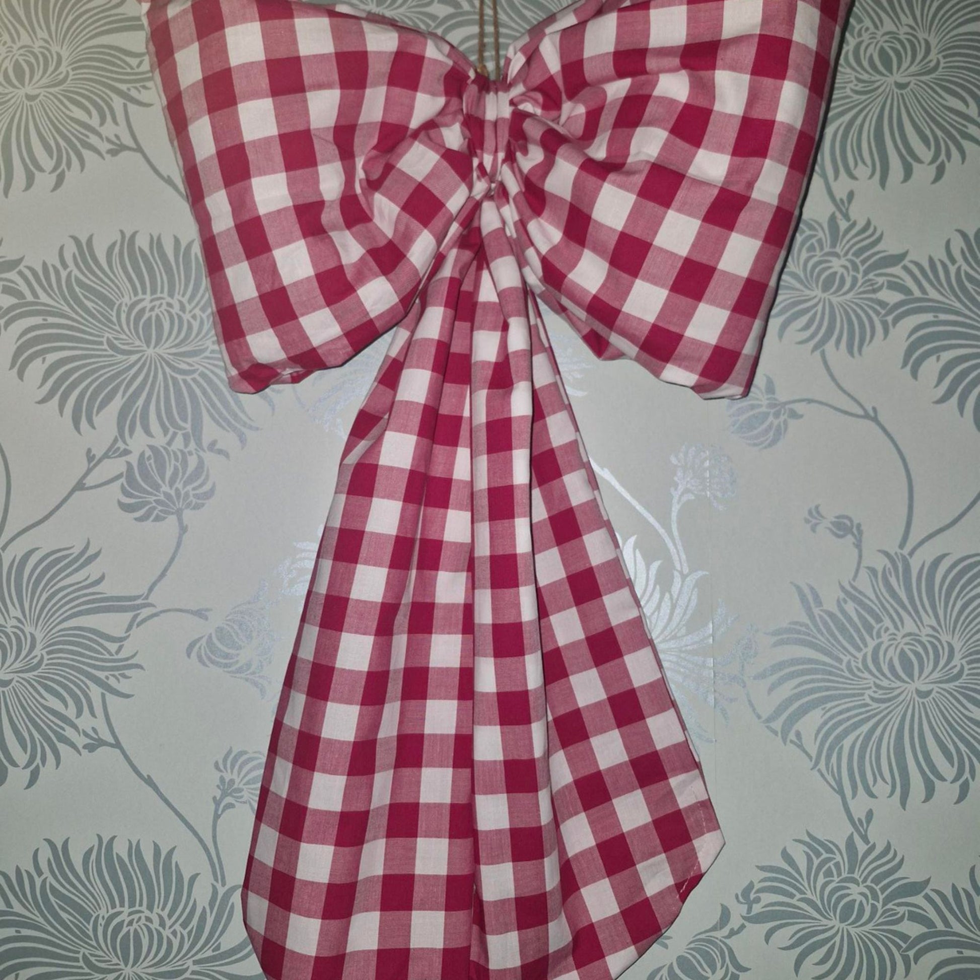 Red and white checkered bow on a floral-patterned wall