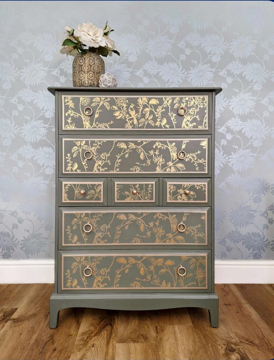 A Stag Minstrel tall boy painted in Carriage House green featuring a chinoiserie stencil and metallic pinstripe details to the drawer fronts.