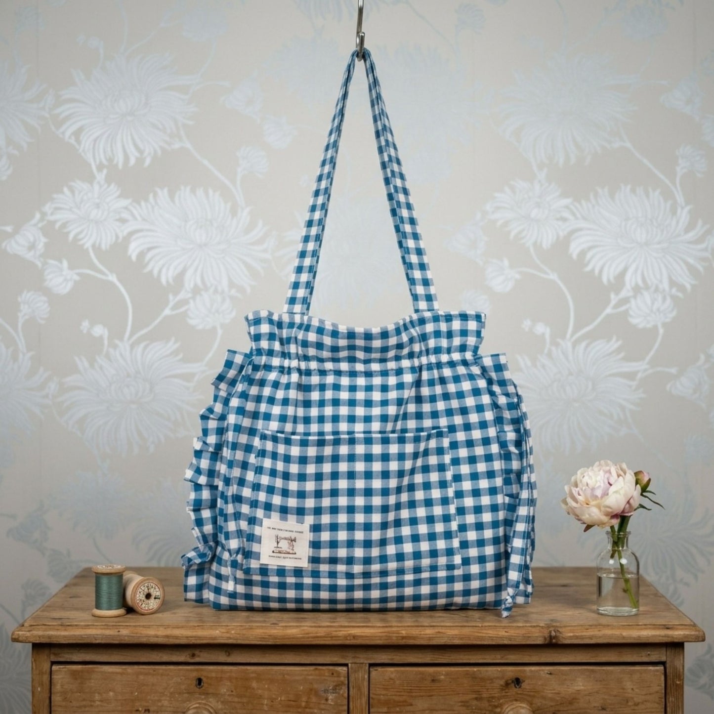 Teal gingham tote bag staged on a vintage chest of wooden drawers.