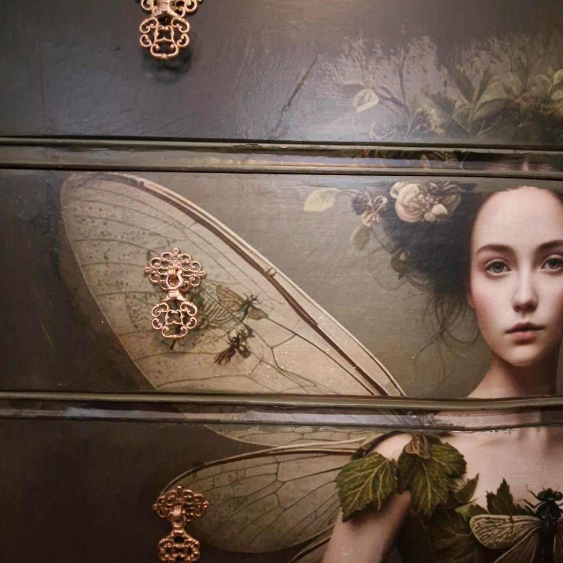 Ethereal fairy decoupage chest in mossy Bayberry with bronze hardware, styled in a calm bedroom setting.