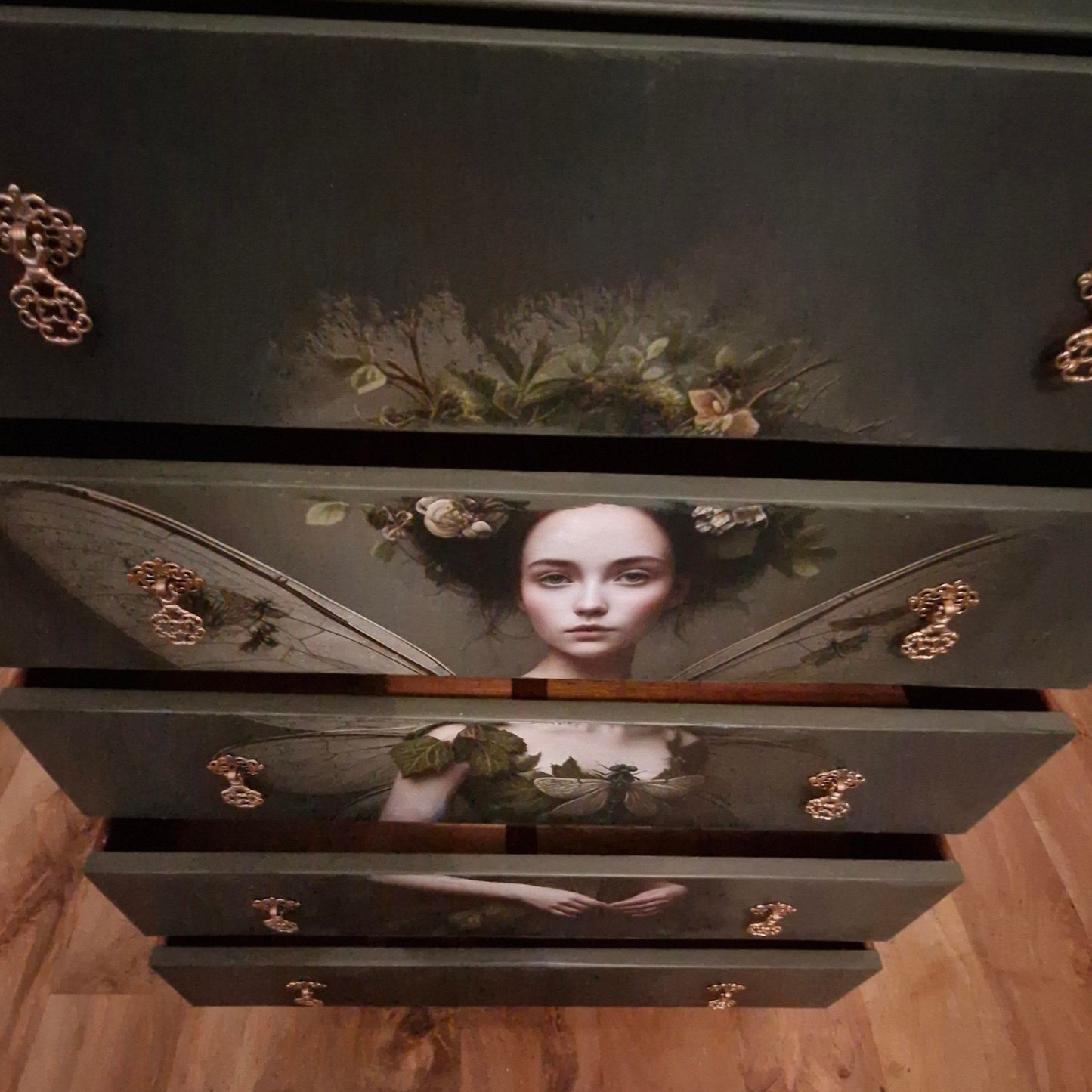 Ethereal fairy decoupage chest in mossy Bayberry with bronze hardware, styled in a calm bedroom setting.