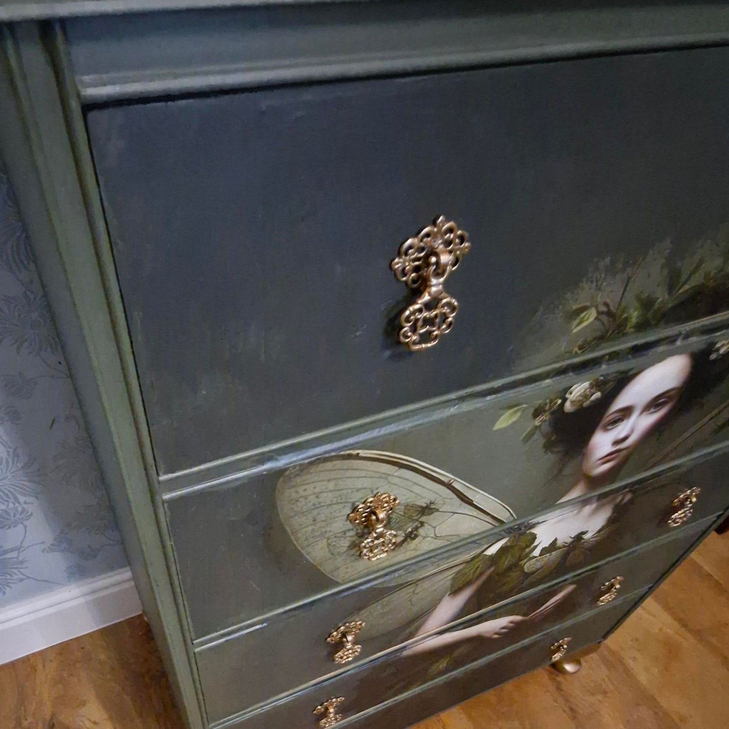 Ethereal fairy decoupage chest in mossy Bayberry with bronze hardware, styled in a calm bedroom setting.