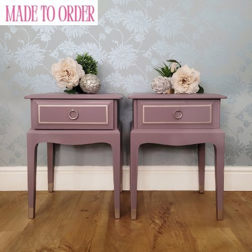 A pair of hand-painted Stag Minstrel bedside tables in Lavender Haze with champagne metallic detailing and lavender toile-lined drawers, styled against a floral wallpaper background.