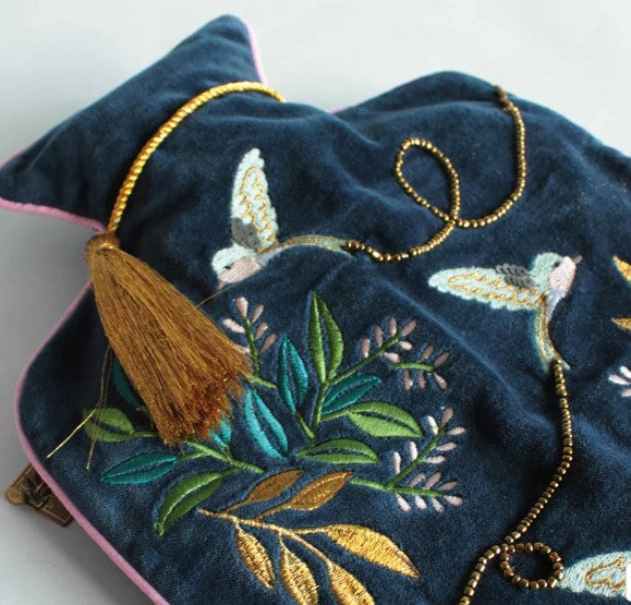 Close-up of swallow embroidery and beading on navy velvet hot water bottle cover, cotton lined.