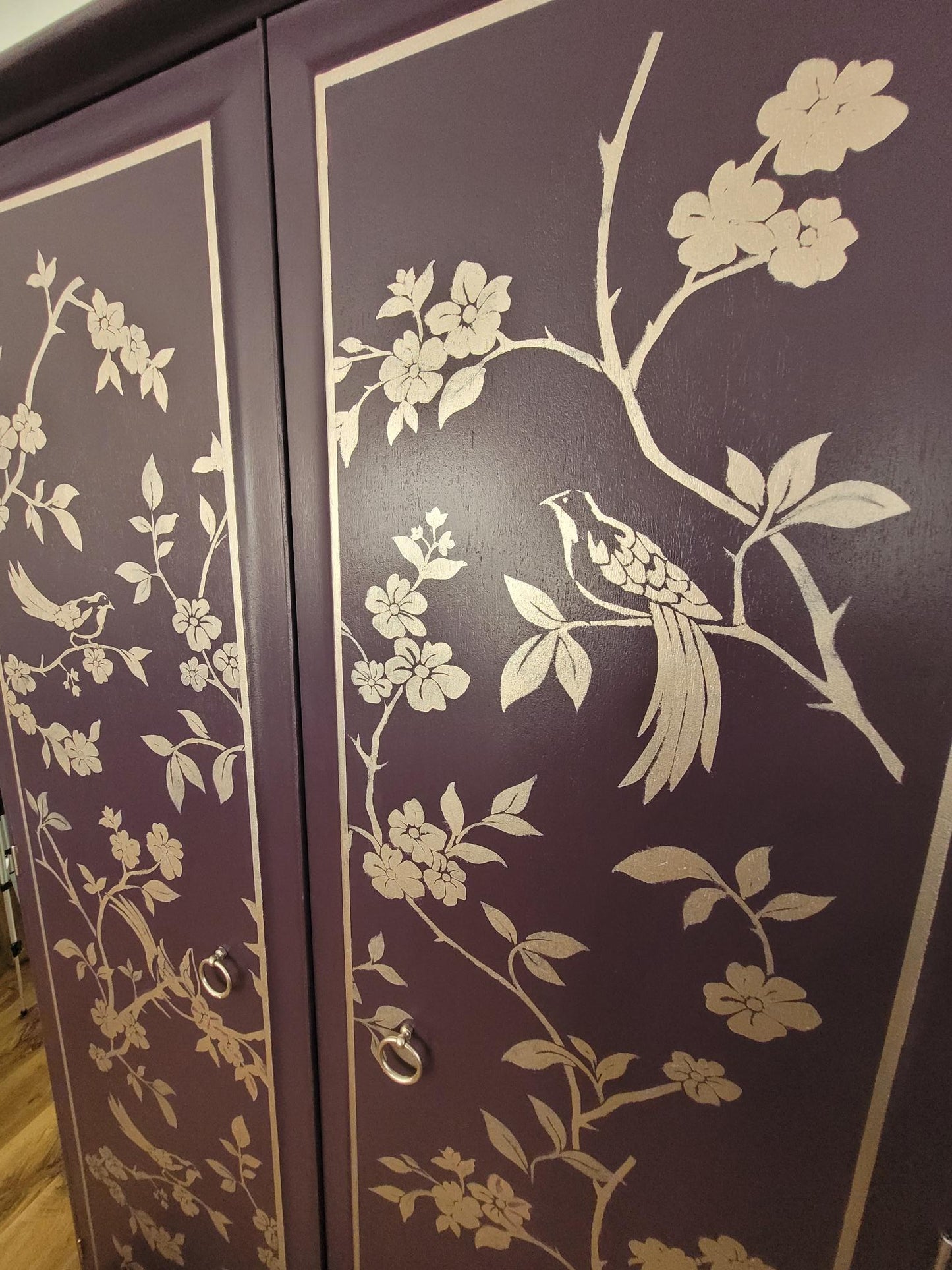 Close-up of gold chinoiserie bird and floral design on Velvet Plum Stag Minstrel wardrobe doors